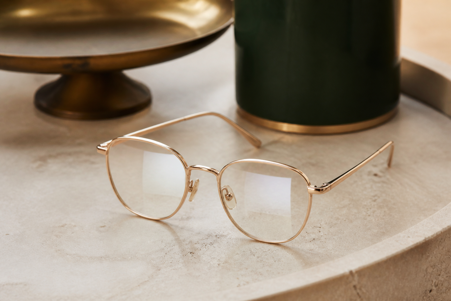 Champagne metal eyeglasses on warm cream stone